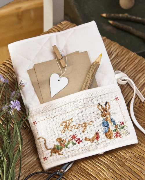 Housse de carnet de santé (24 x 17 cm) en coton piqué matellassé blanc, biais à la dentelle, à broder sur Aïda 5,5 ou lin 12 fils. Fabrication française. Grilles dans les mooks Pierrot-Lapin et Le roi des éléphants.