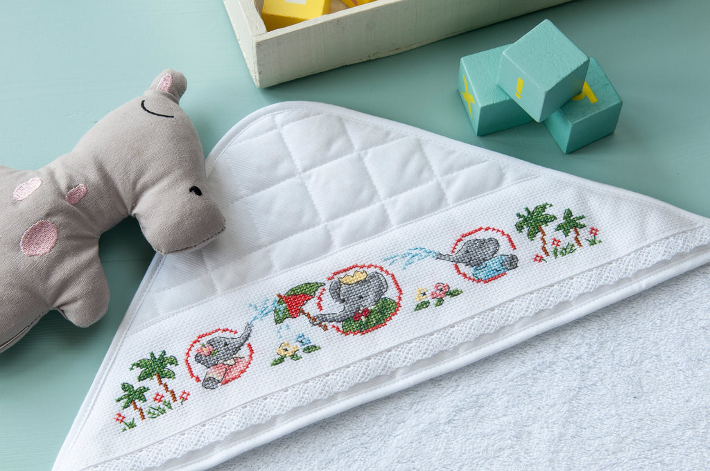 Sortie de bain 78 x 78 cm en éponge 100 % coton avec capuche matellassée, à broder sur Aïda 5,5 points, biais à la dentelle. Fabrication française. Grille dans les mooks Pierrot-Lapin n°1 & n°2 et Le roi des éléphants n°1.